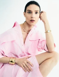 Model Kati Nescher wearing a pink shirt and gold jewellery against a clean white seamless studio background for Joaillerie by Les Echos.
