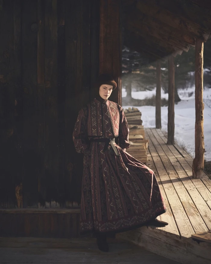 Model Ida Heiner in patterned winter coat standing on a wooden porch for Loro Piana Holiday 2026 campaign.