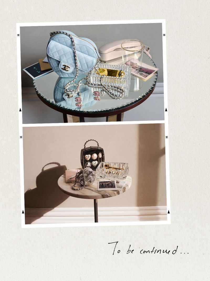 Heart-shaped Chanel bag, crystal boxes, and accessories on round tables with a Polaroid-style frame on an off-white background.