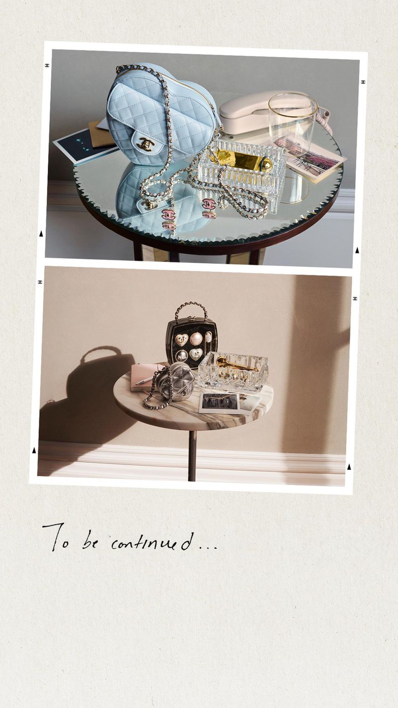Still life of luxury handbags and accessories arranged on side tables, featuring a Chanel heart-shaped purse and crystal decor.