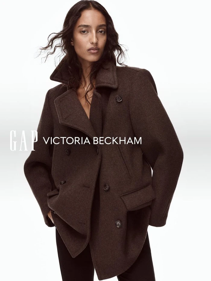 Mona Tougaard wearing a brown double-breasted coat against a plain white seamless studio background for Gap and Victoria Beckham.