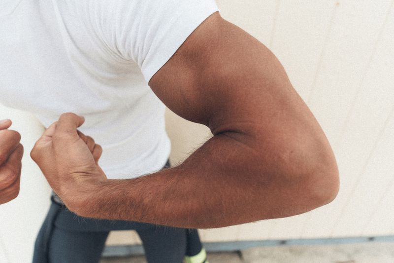 Close-up of a man flexing his muscular bicep wearing a white t-shirt for MMScene project Morning Mist