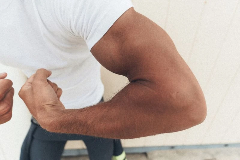 Close-up of a man flexing his muscular bicep wearing a white t-shirt for MMScene project Morning Mist