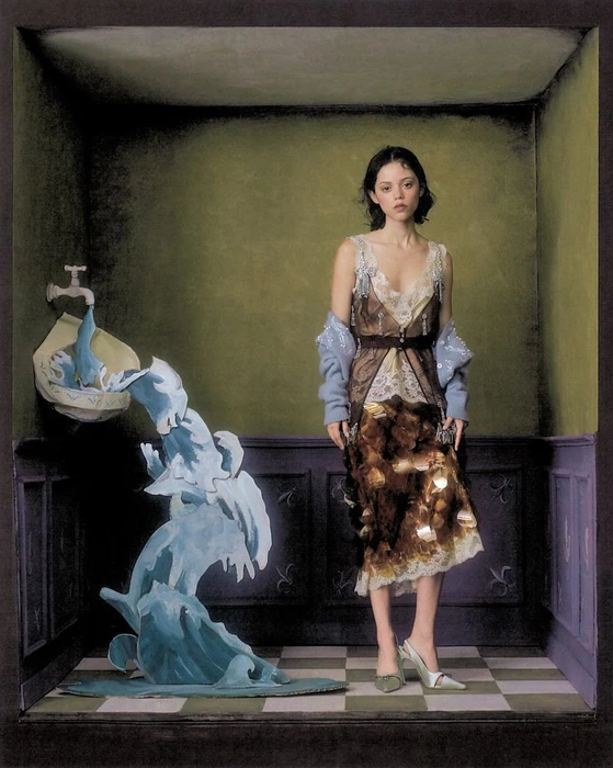 Jenna Ortega posing inside an illustrative room beside a sculptural wall-mounted tap pouring a painted blue water wave