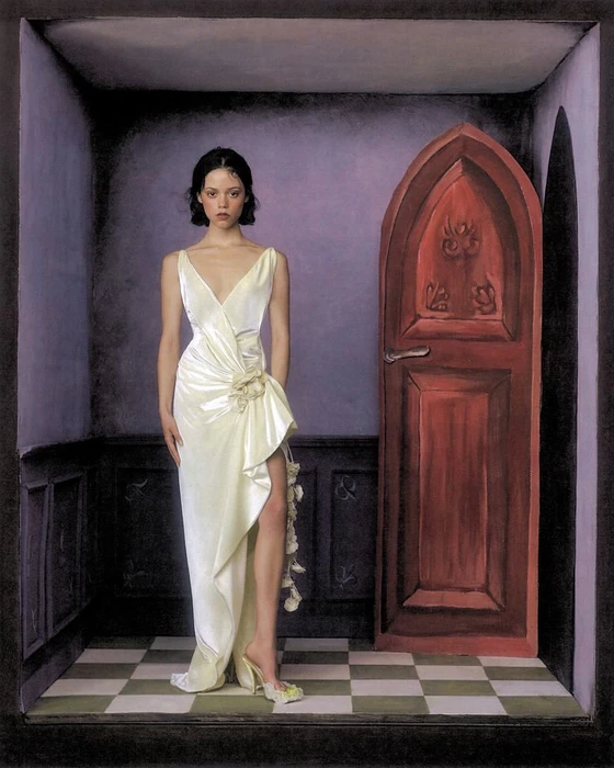 Jenna Ortega in a white satin gown standing before a red wooden door inside a room with checkerboard flooring.
