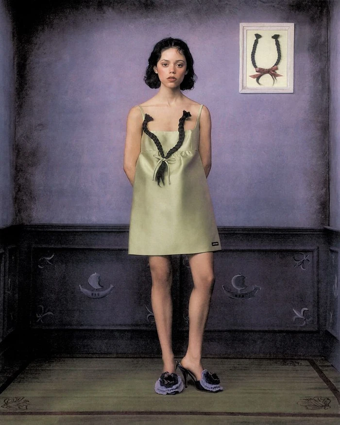 Jenna Ortega in a pale green minidress with braided hair straps standing in a purple room for American Vogue