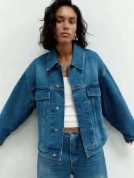 Model wearing a blue denim jacket and matching jeans against a plain white background for Elle UK.
