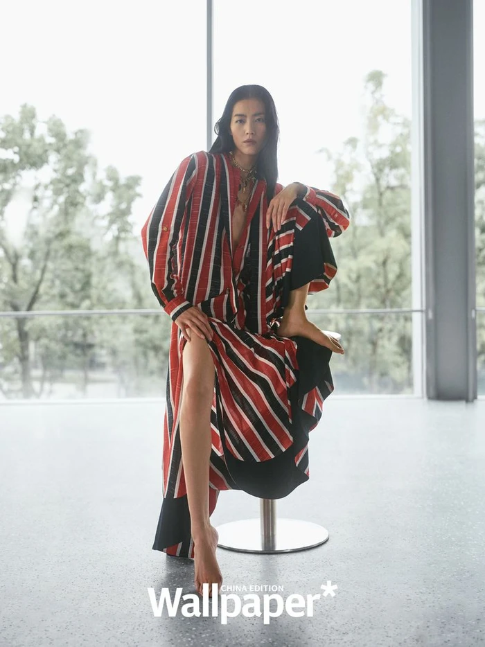 Model Liu Wen wearing a red, white, and black striped dress seated on a stool inside a bright modern space for Wallpaper China.