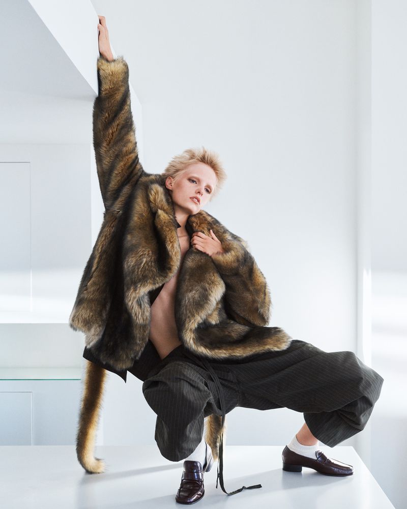 Model Gretchen Easterwood wearing a fuzzy faux fur coat and dark trousers posing in a bright interior for Re-Edition