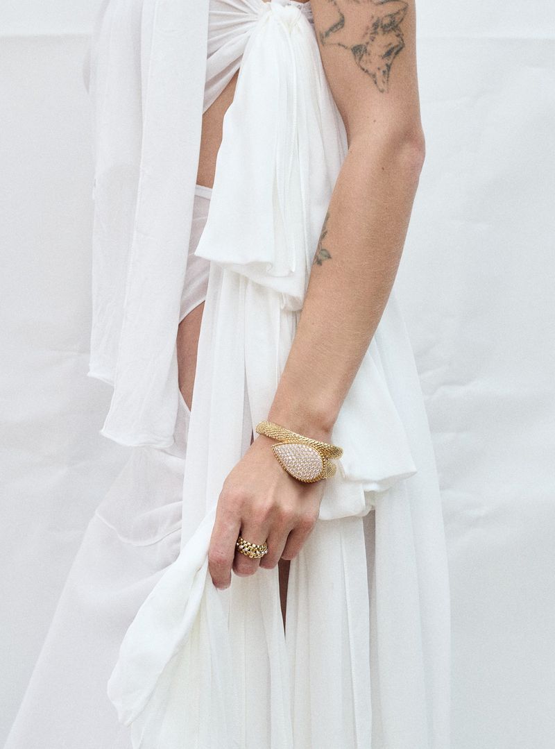 Close-up of adult woman wearing a white gown with jewelry on her hand in a brightly lit indoor setting.