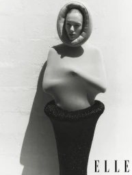 Model wearing sculptural avant-garde apparel against a plain light wall for Elle UK fashion editorial