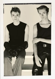 Two male models in black tank tops sitting against a light background for Le Mile Magazine editorial