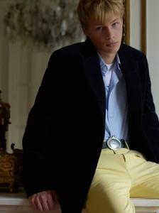 Model Orlando Spence in a dark jacket, blue shirt, and yellow trousers for Dior Men photographed by Theo Wenner