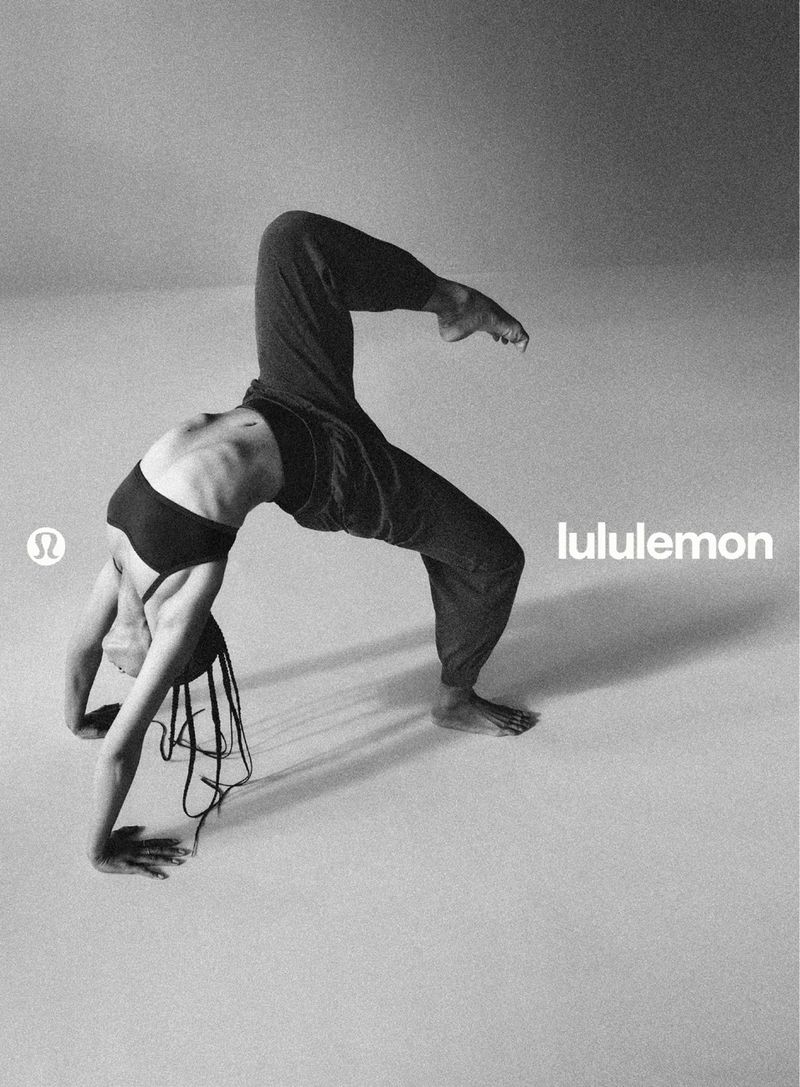 Model Dakota Moore holding a wheel pose in sportswear against a seamless studio background for Lululemon
