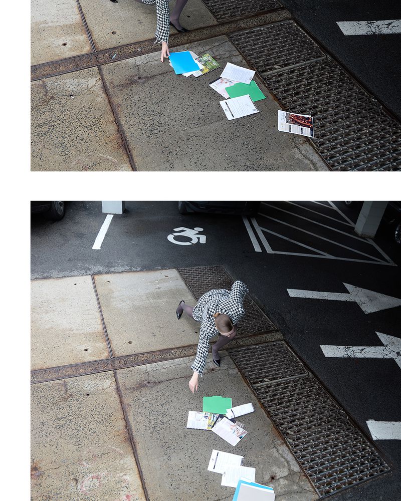 Overhead shot of person dropping papers on sidewalk near parking space, creating a sense of accidental mess in urban environment.