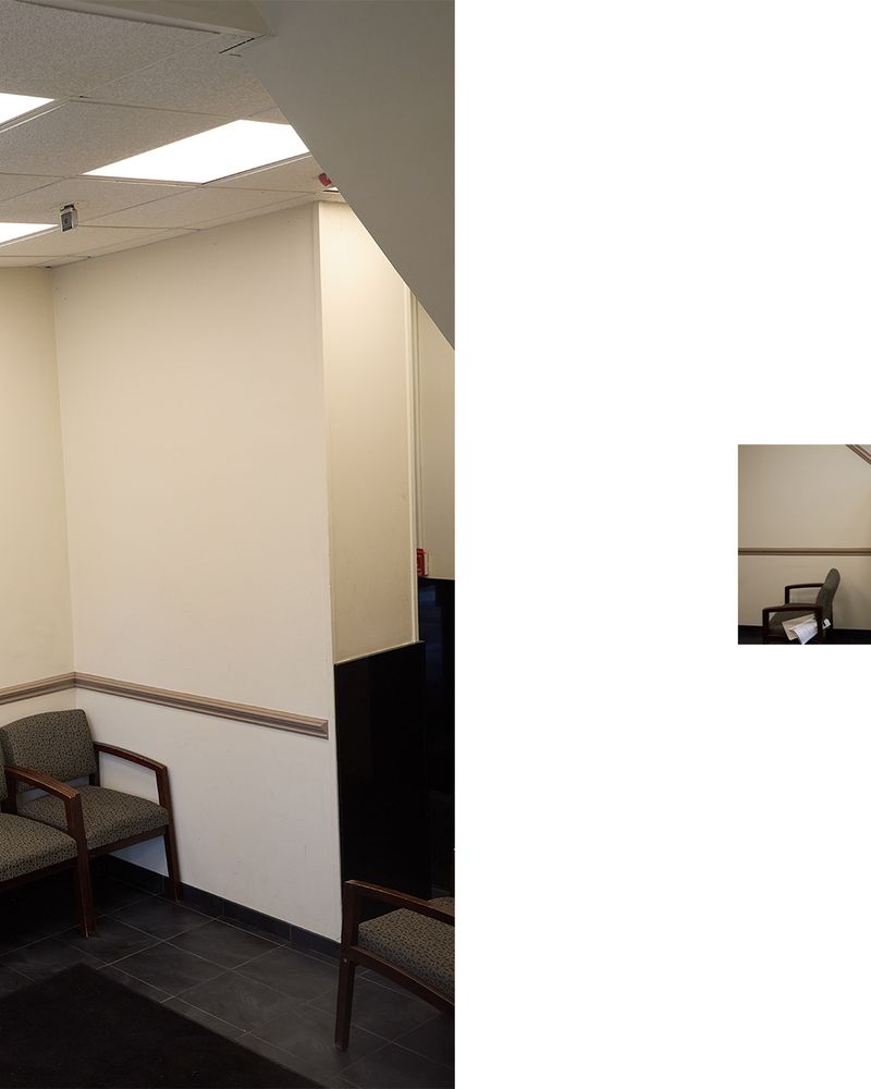 Indoor waiting area with chairs against a wall under bright fluorescent lighting. Interior of a commercial or healthcare facility.