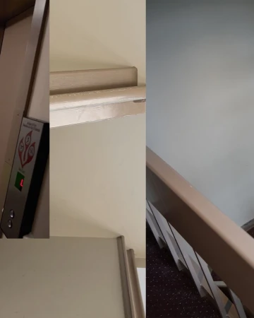 Interior view showing an elevator control panel with lit floor number, adjacent wall, and railing with stairs in the background.