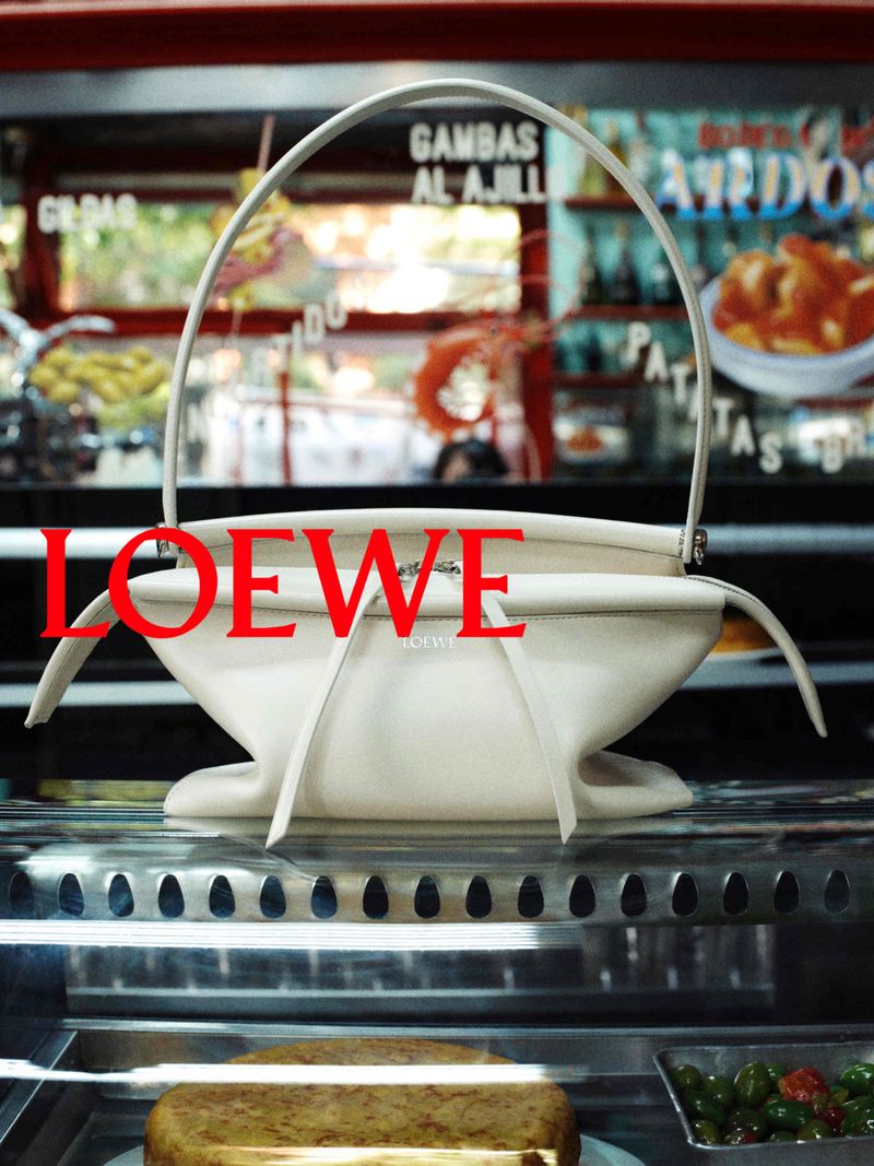 Off-white leather handbag on a glass display counter with red Loewe typography overlay