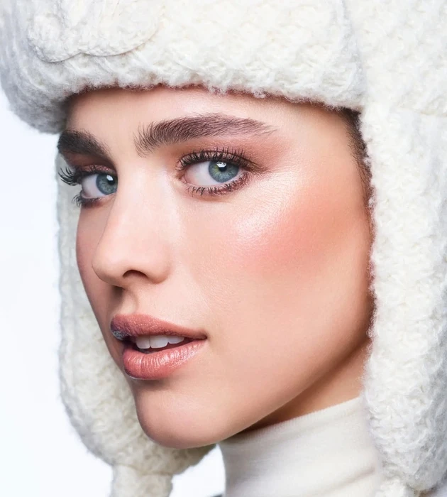 Close-up portrait of Margaret Qualley wearing a white knit trapper hat for Chanel's Holiday 2026 Makeup Campaign