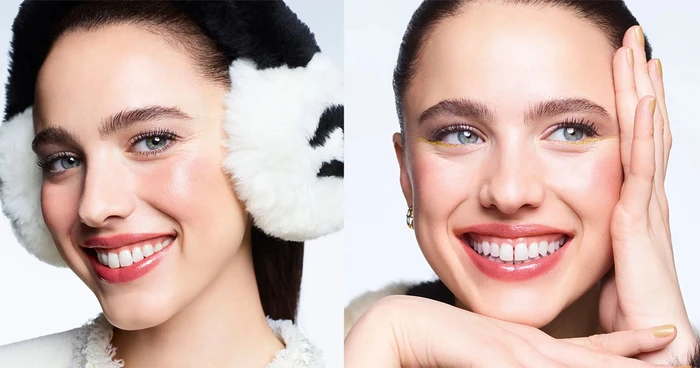 Margaret Qualley wearing white earmuffs with black details and smiling for Chanel's Holiday 2026 makeup campaign portrait.