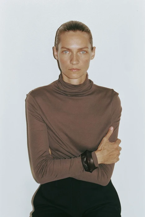 Model Karolin Wolter wearing a brown turtleneck and dark trousers against a plain white background for H&M.