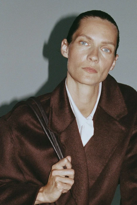 Model Karolin Wolter in a dark brown coat against a grey studio backdrop for H&M Stone Blush project shot by Pauline Suzor