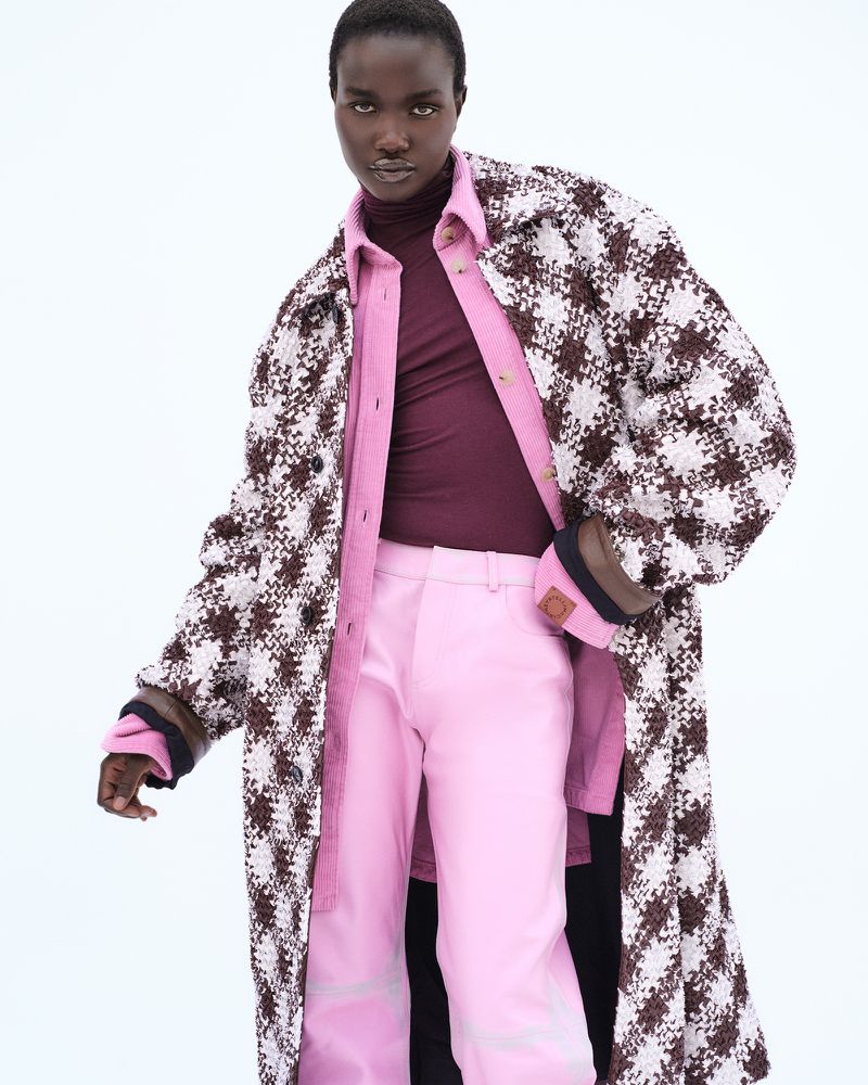 Model Akon Changkou wearing houndstooth coat over pink trousers against a plain white background for Vogue Espana.