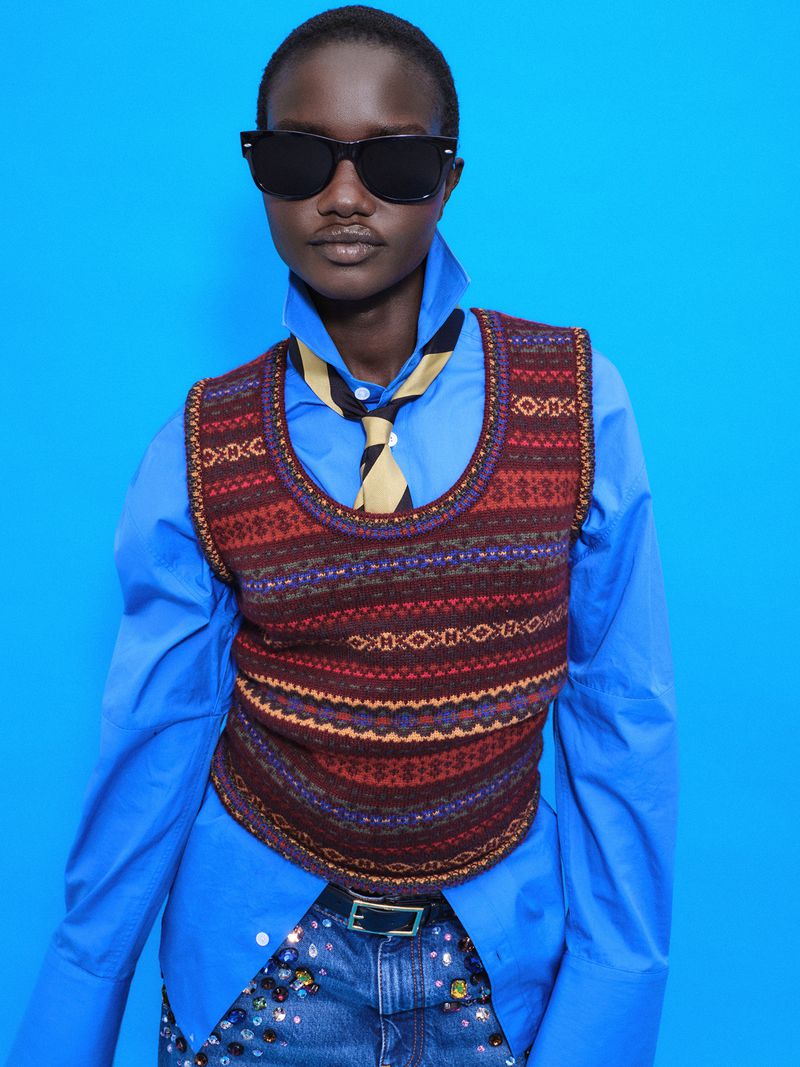 Model Akon Changkou wearing a patterned knit vest over a blue shirt against a vivid blue background