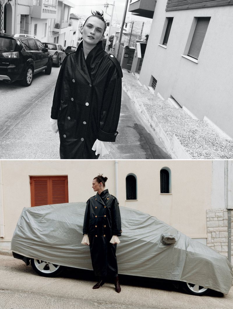 Model Lara Mullen wearing a black leather trench coat posing outdoors on a street for Vogue Greece urban armor editorial
