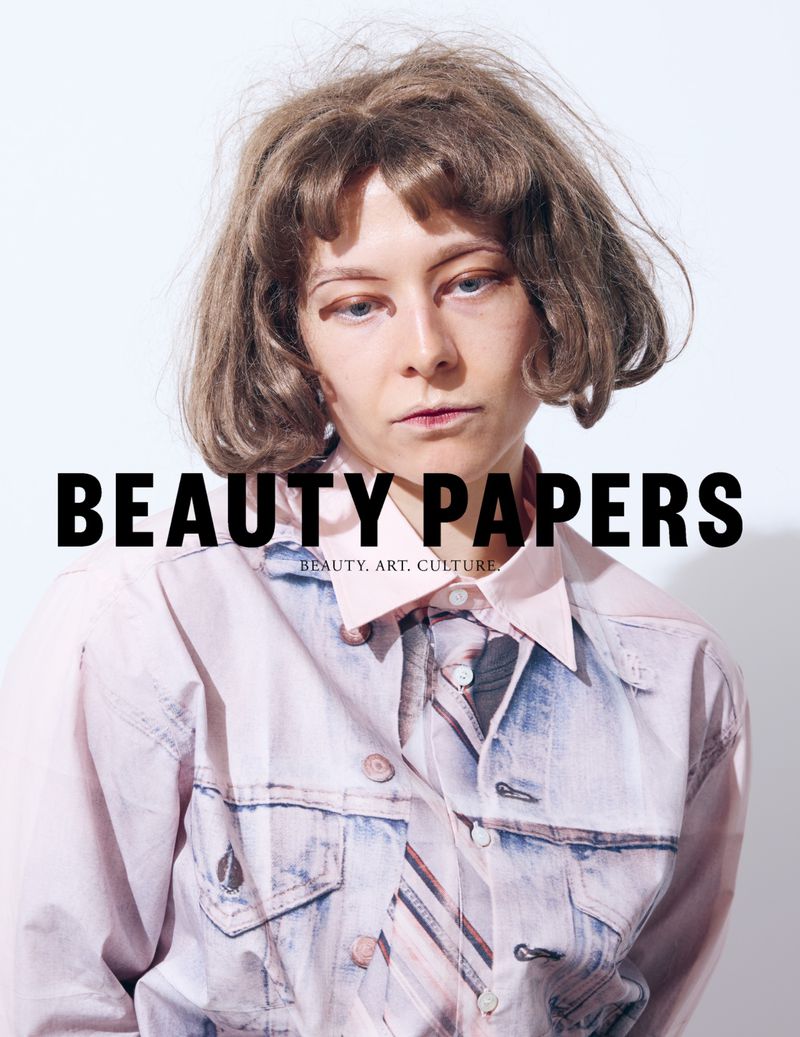 Portrait of Emma D'Arcy wearing a printed shirt against a plain white background for Beauty Papers.