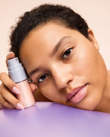 Adult female posing with Fenty Skin Start'r Set product. Light skin, light pink nails, soft focus, studio lighting, cosmetic skincare.