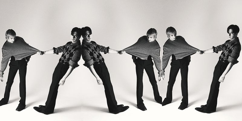 Monochrome image of a young man in repeating poses pulling at his sweater, set against a stark white background in a studio.