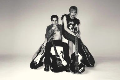 Two musicians posing with guitars against a plain studio background for The Collector Magazine editorial.