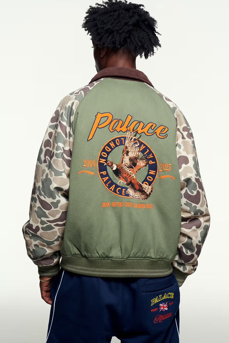 Man facing away wearing green Palace jacket with camouflage sleeves and dark blue pants against a white background in a studio.