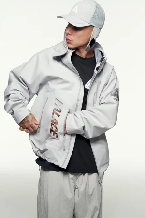 Fashion shot of a man in a light gray jacket and pants, wearing a matching cap against a clean white background in a studio.