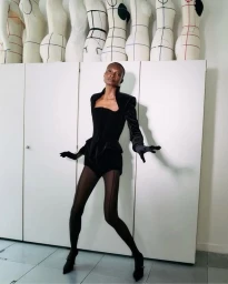 Model Debra Shaw in black Mugler outfit posing in front of tailor mannequins for Paris Atelier