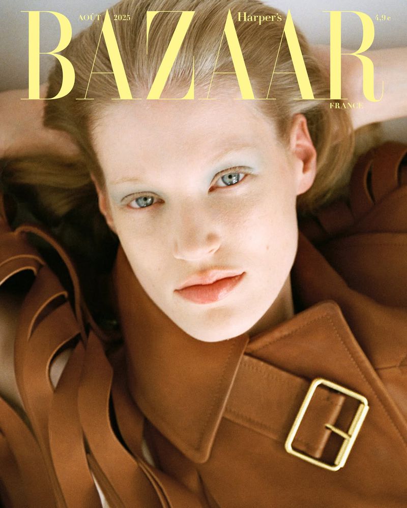 Close-up magazine cover featuring a fair-skinned woman with blue eyes and a brown trench coat, framed by the magazine's yellow logo.