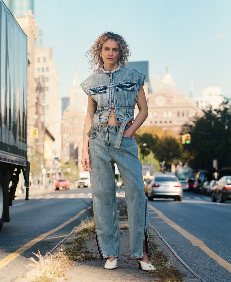 Aliz Menyhert wearing a light wash cropped denim vest and wide-leg jeans on an urban street for 3.1 Phillip Lim.