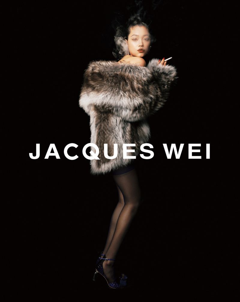 Fashion portrait of a woman in a fur coat smoking, showcasing Jacques Wei design against a stark black backdrop with dramatic lighting.
