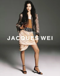 Model wearing a patterned jacket, draped skirt, and strappy heels against a neutral studio background in the Jacques Wei campaign