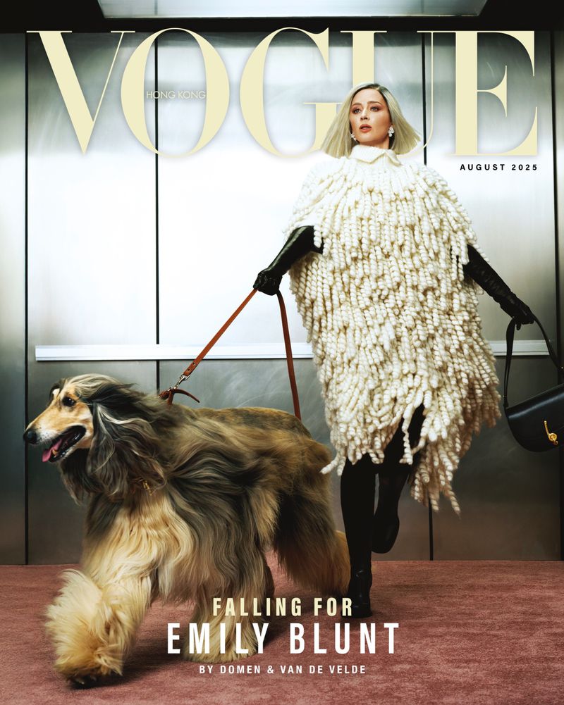 Magazine cover of Vogue Hong Kong featuring Emily Blunt and an Afghan Hound dog, indoor in an elevator, wearing knitwear and holding a purse.