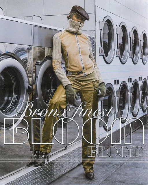 A woman wearing olive-toned pants and jacket with a wool turtleneck poses in front of commercial washing machines for a fashion editorial.