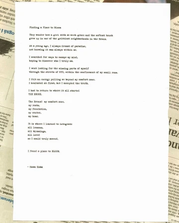 Poem typed on white paper in a serif font. The paper sits on newspaper print with cream and dark gray hues in indoor setting.