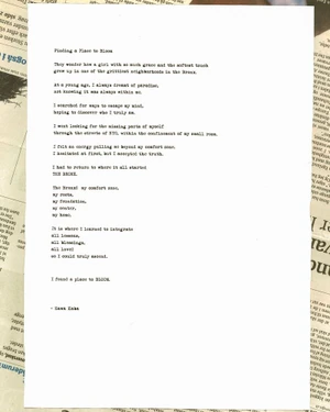 A sheet of white paper with a typed poem titled Finding a Place to Bloom resting on a newspaper background.
