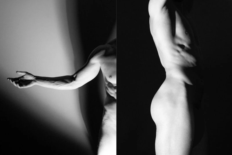 Artistic monochrome studio shot of a nude adult male torso, revealing muscular build and dynamic light play across skin tones.
