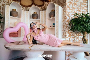 Model in a pink rosette dress and headscarf lying on a marble table for Cosmopolitan Middle East.