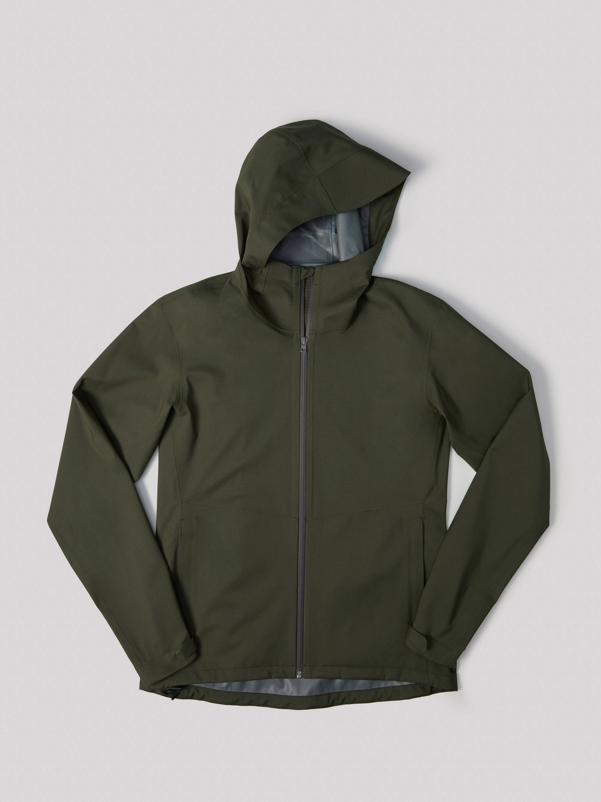 Olive green hooded waterproof zip-up jacket laid flat on a light grey seamless studio background.