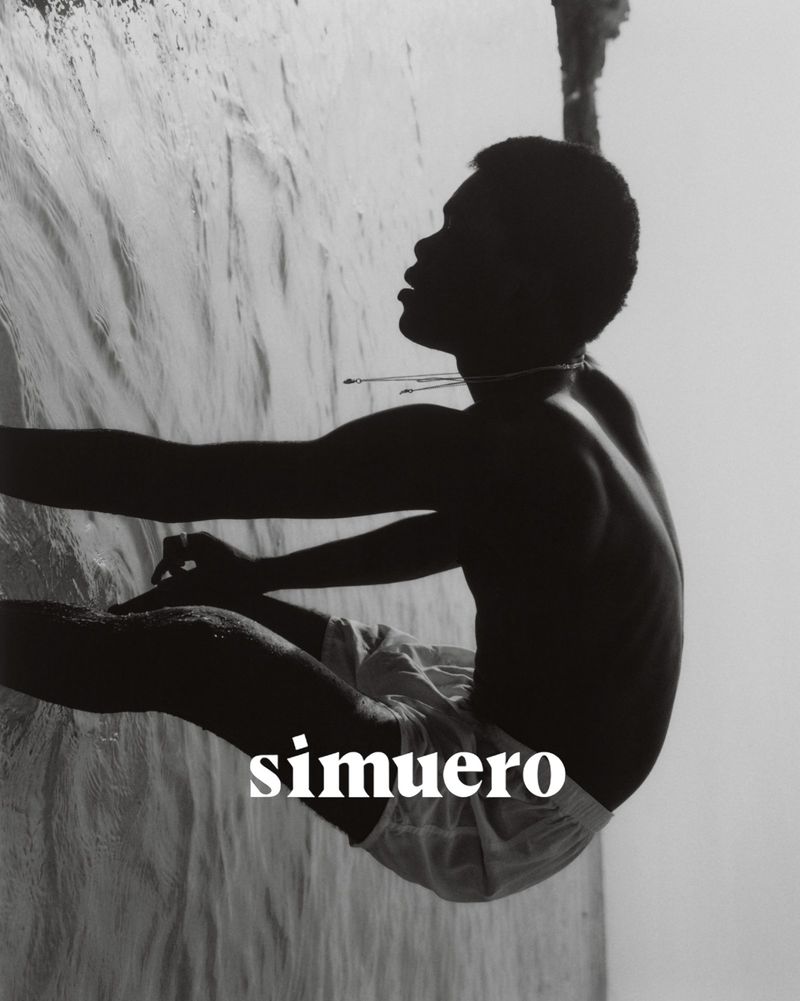 Monochrome portrait of a young man at the water's edge, gazing upwards in side profile, with visible text 'simuero' layered on the image.