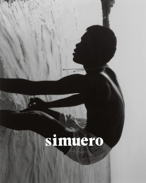 Monochrome portrait of a young man at the water's edge, gazing upwards in side profile, with visible text 'simuero' layered on the image.