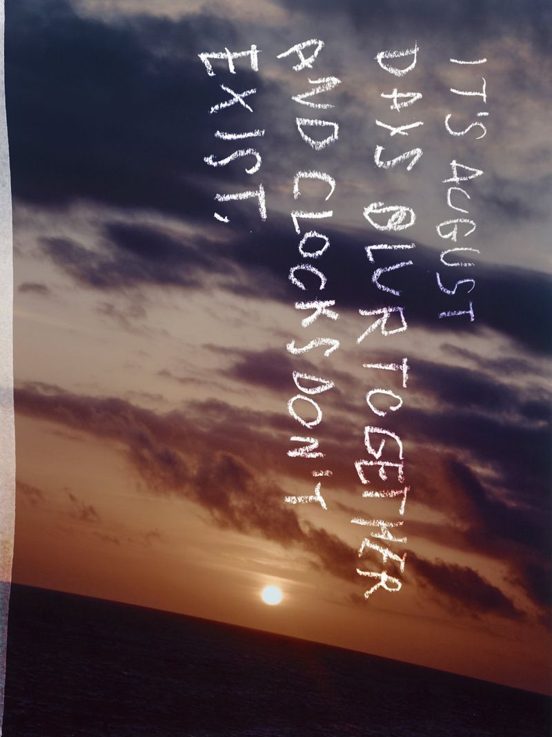 Sunset over the ocean with superimposed text that reads, 'It's August, days blur together, and clocks don't exist,' creating a serene visual.